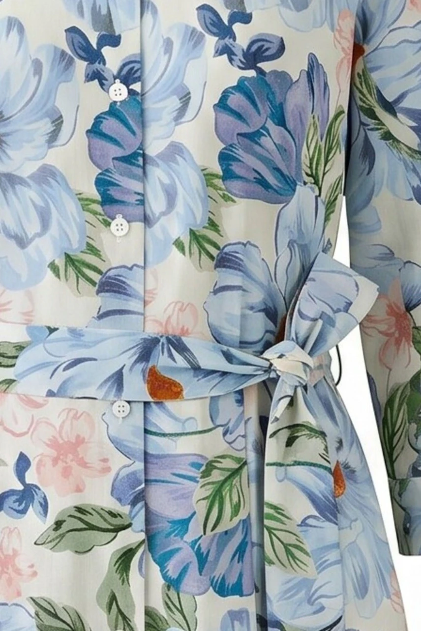 Blumiges Midikleid mit Gürtel: Detailansicht des floralen Musters in Blau und Rosa auf weißem Stoff.