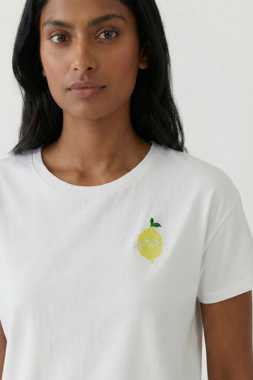 Casual women's T-shirt: Woman in white T-shirt with lemon print, simple and fresh look.