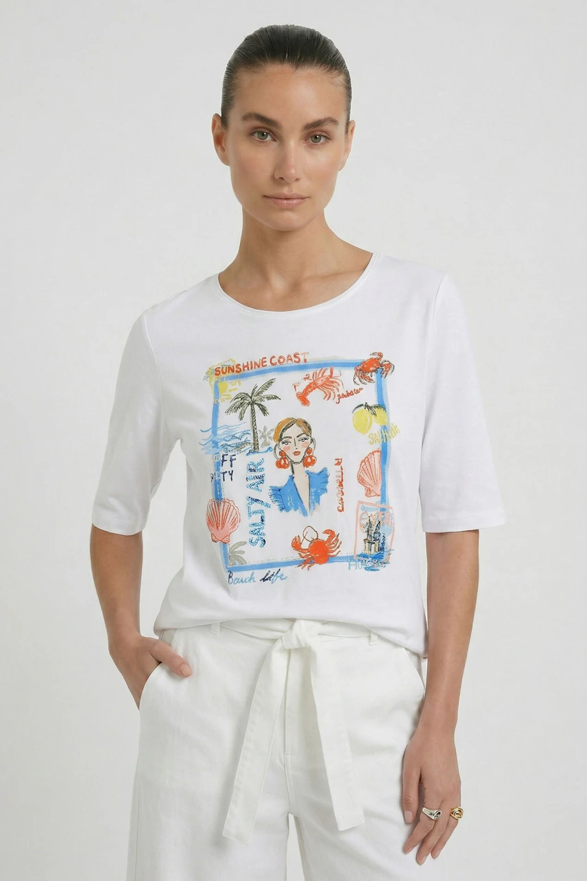 Weißes Damen-T-Shirt: Frau trägt T-Shirt mit buntem Print, kombiniert mit weißer Hose, lässig und modern.