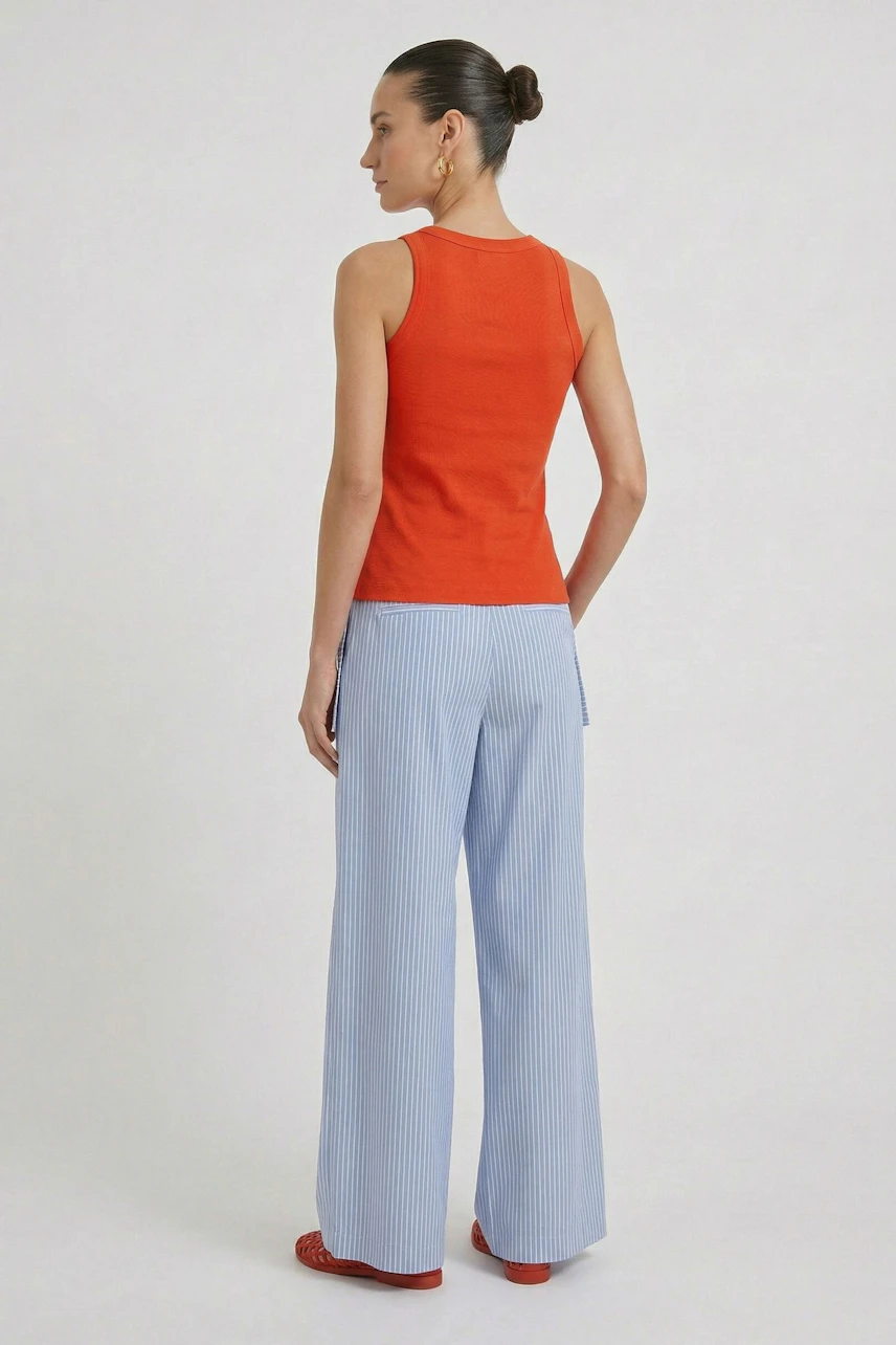 Woman in red tank top and light blue wide-leg pants, viewed from the back.