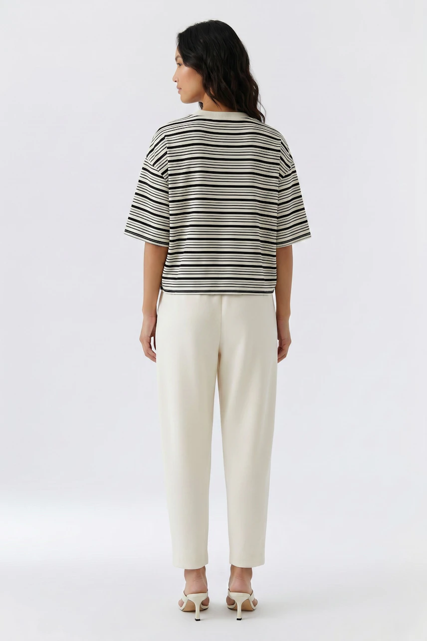 Striped T-shirt: Woman in a casual black and white striped T-shirt and white pants, viewed from the back.