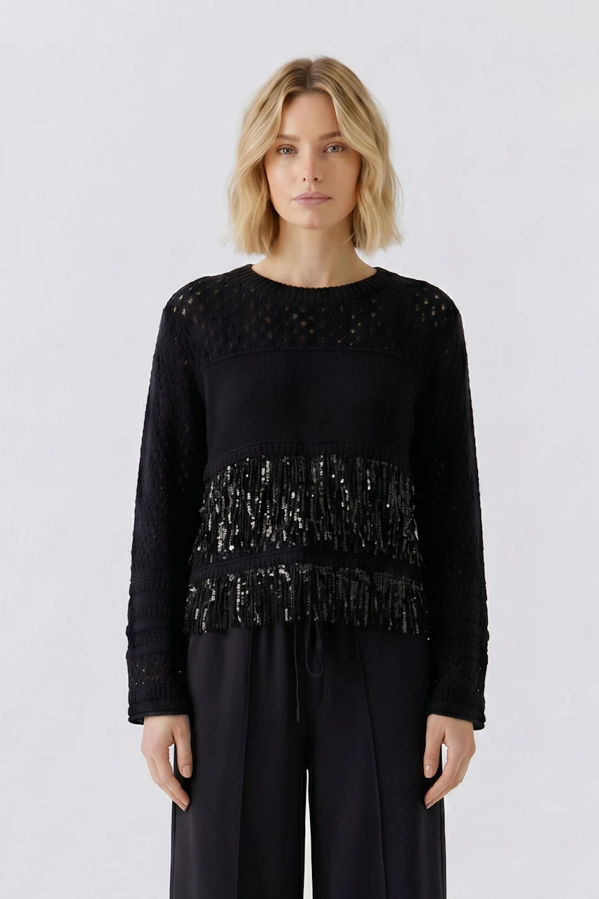 Casual women's pullover: Woman in black textured pullover with subtle fringe detail, paired with wide-leg pants.