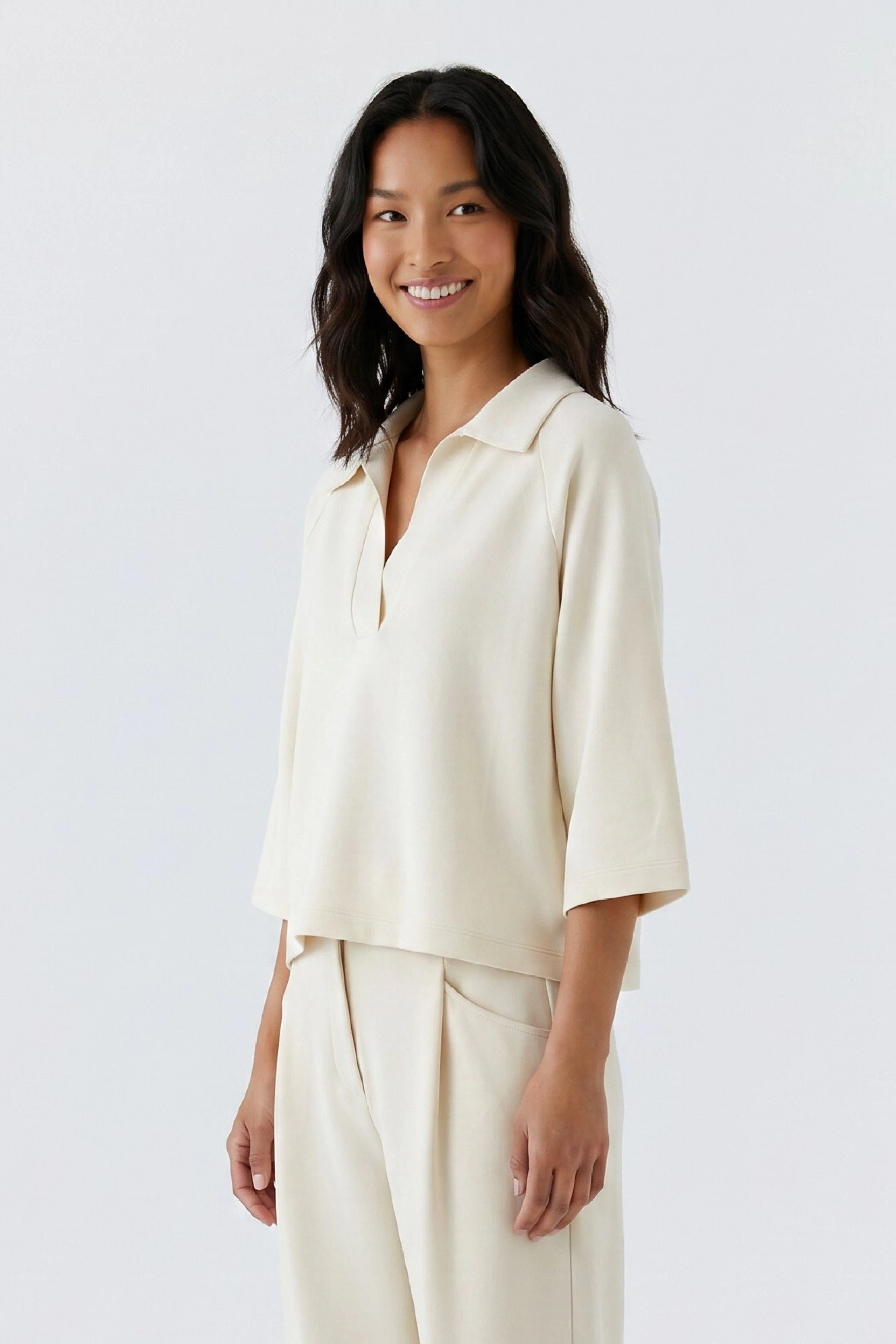 Casual women's sweatshirt: Woman in a cream sweatshirt with relaxed fit and wide sleeves, smiling confidently.