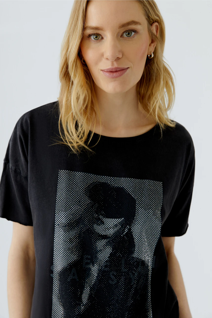 Casual women's T-shirt: Woman in black T-shirt with graphic print, relaxed and stylish look.