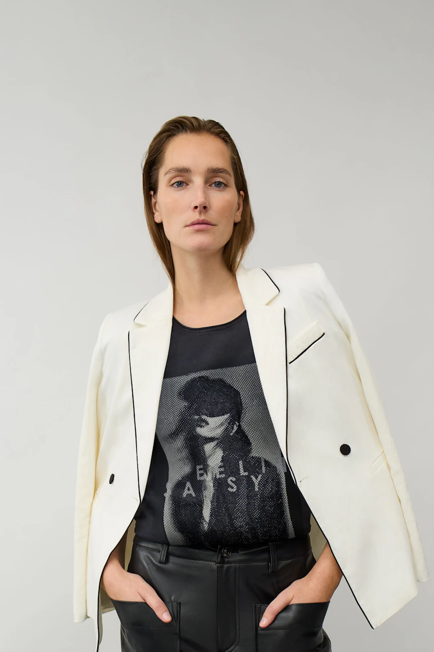 Casual T-shirt: Woman in graphic T-shirt under white blazer, paired with black leather pants, looks confident.