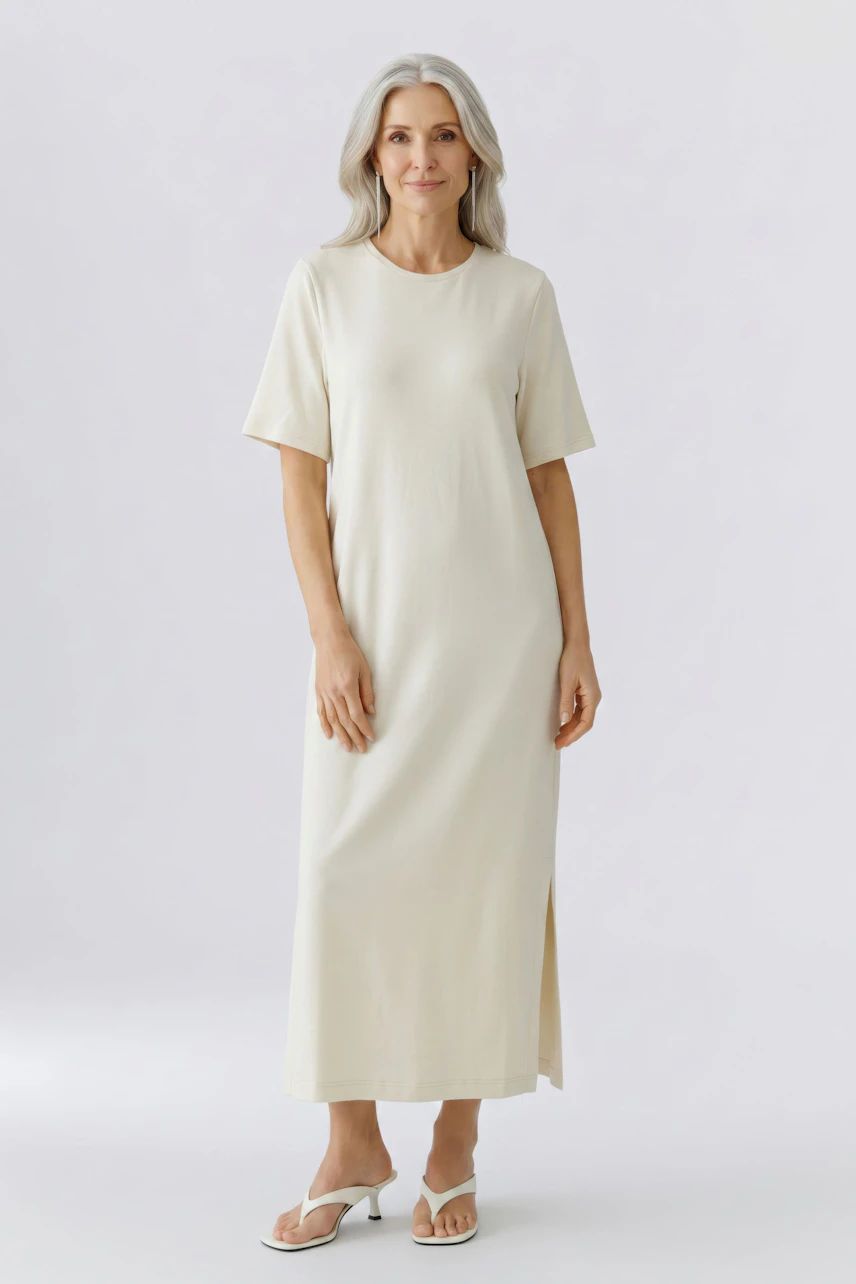 Casual dress: Woman in a cream-colored, short-sleeve dress with side slit, standing confidently.