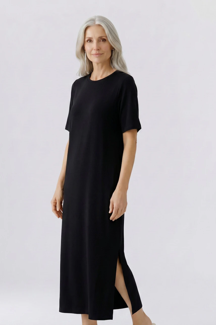 Casual dress: Woman in a black, short-sleeve dress with side slit, standing confidently.
