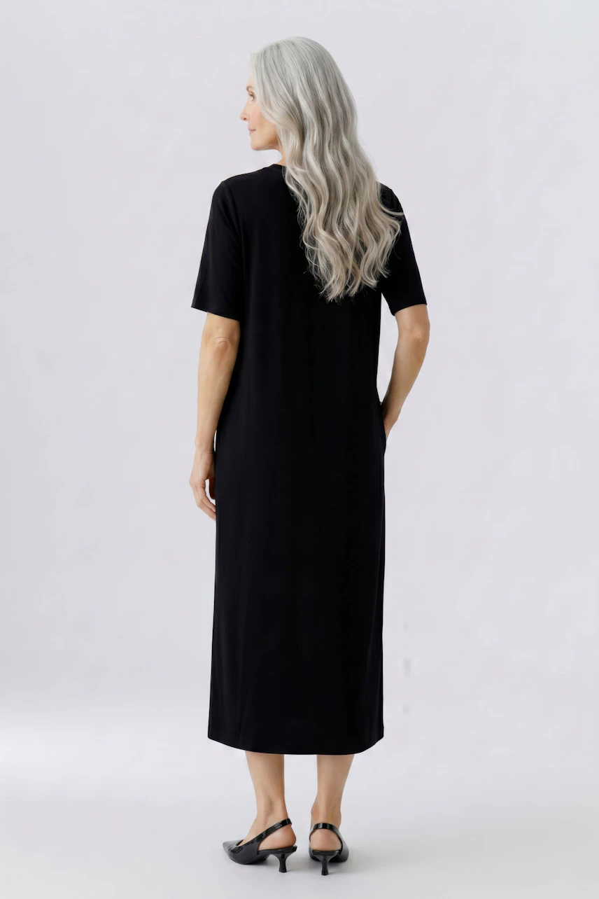 Casual dress: Woman in a black midi dress with short sleeves, standing confidently.