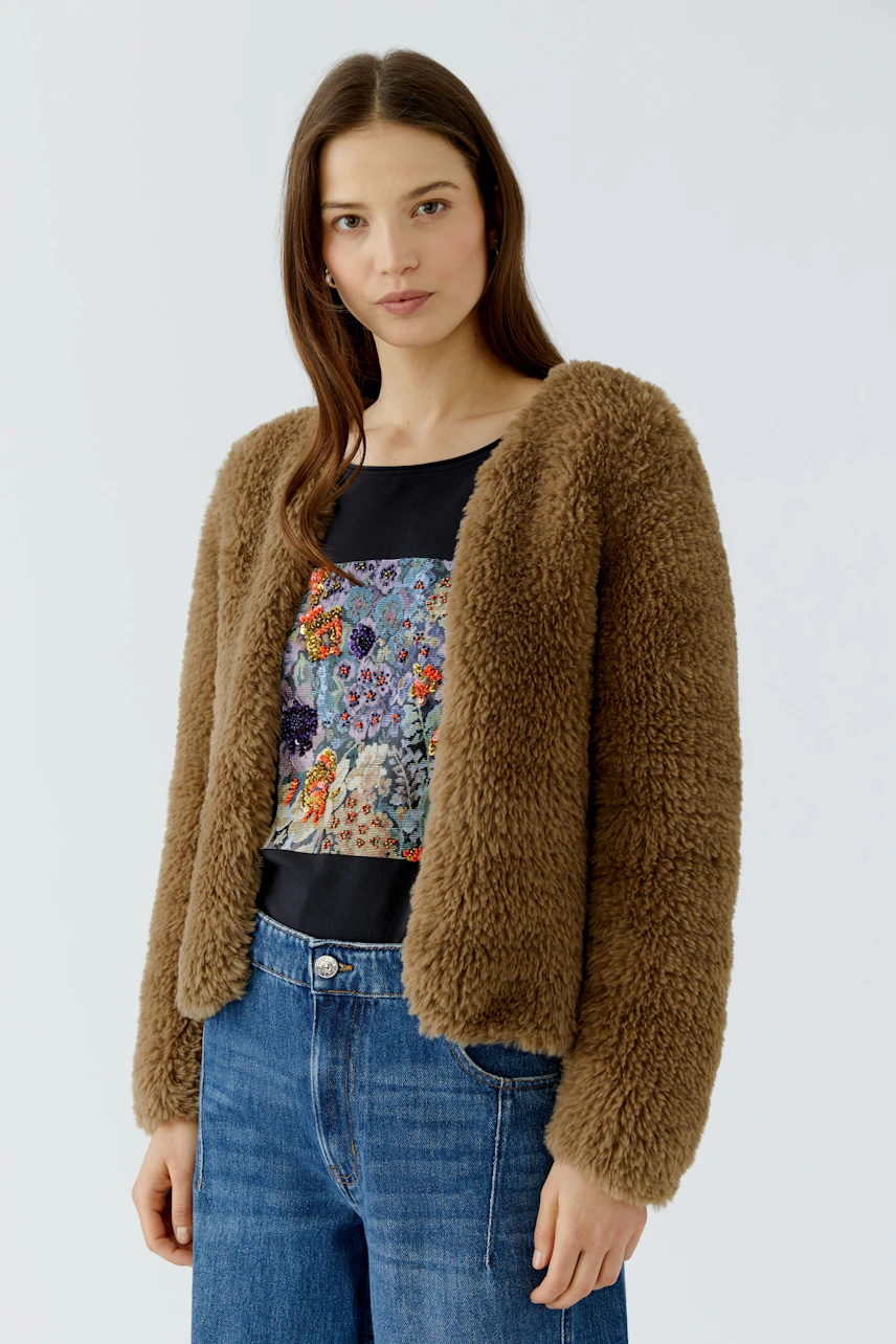 Woman in cozy brown cardigan, floral top, and jeans. Casual and stylish look for everyday wear.