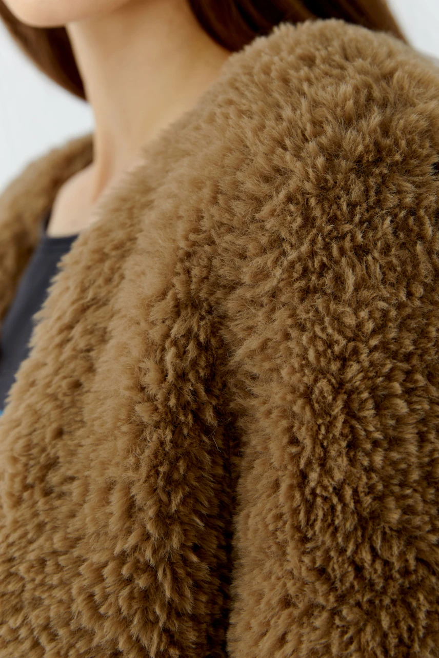 Cozy women's cardigan: Woman in a fluffy brown cardigan, perfect for casual warmth and style.