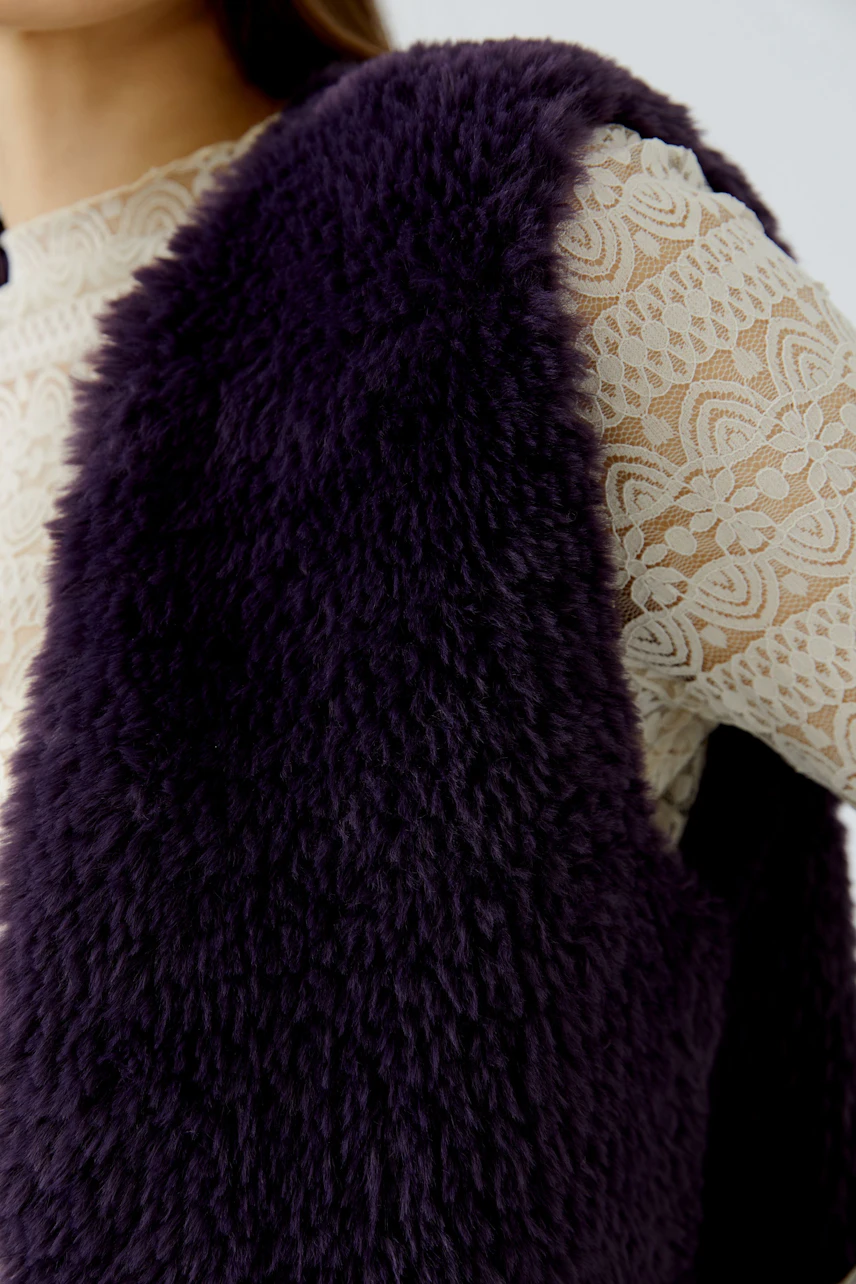 Woman in a fluffy knit vest over a lace top, showcasing a cozy and stylish look.
