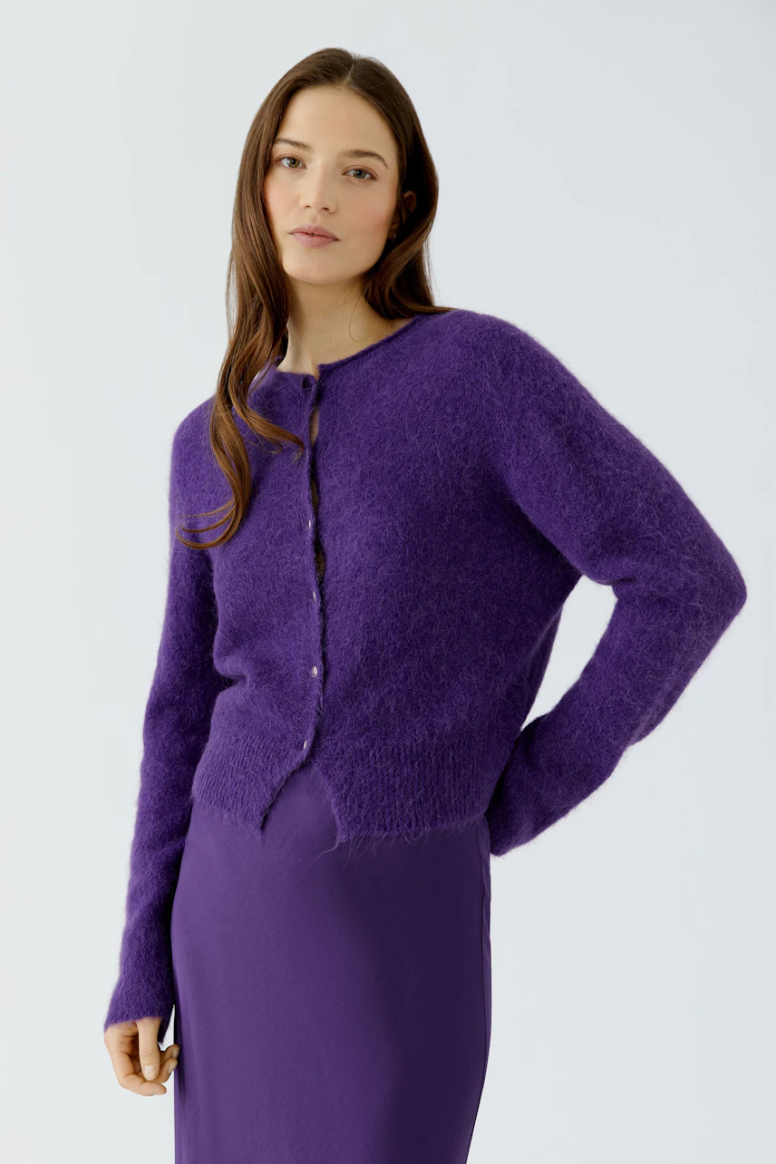 Woman in purple cardigan: A young woman wears a cozy purple knit cardigan over a matching dress.