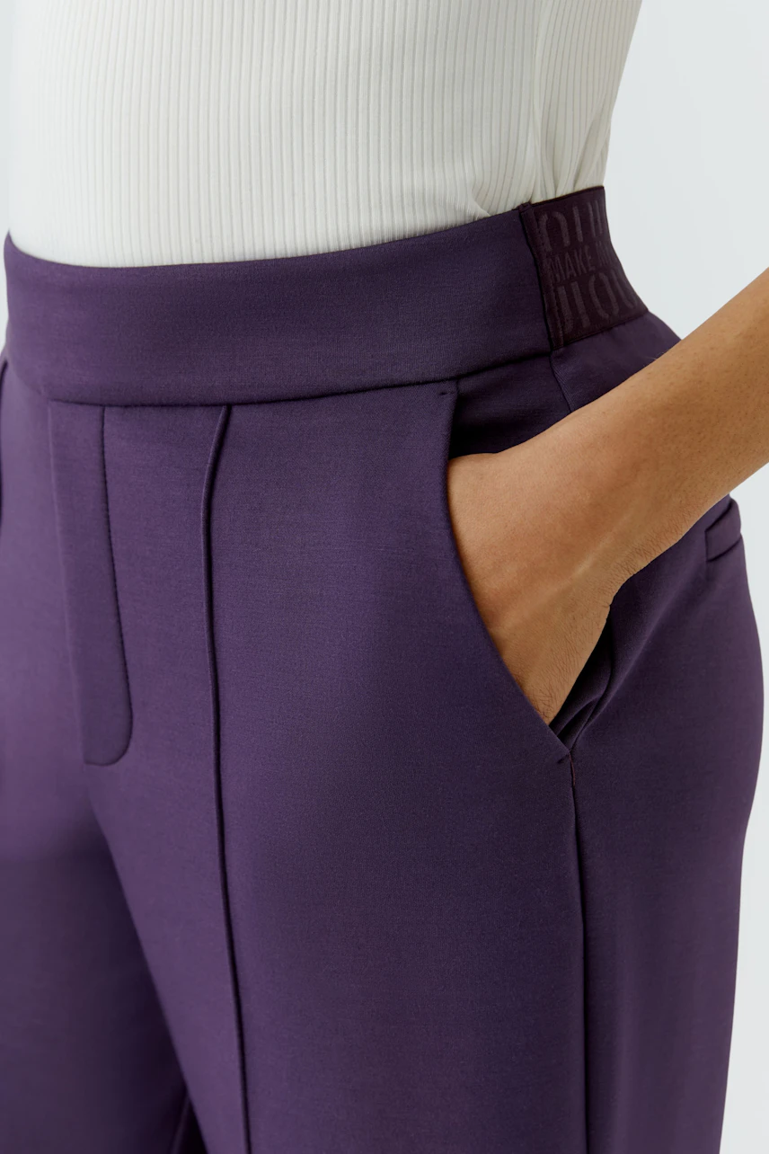 Woman in purple pants with a white top, showcasing a modern and sleek design.