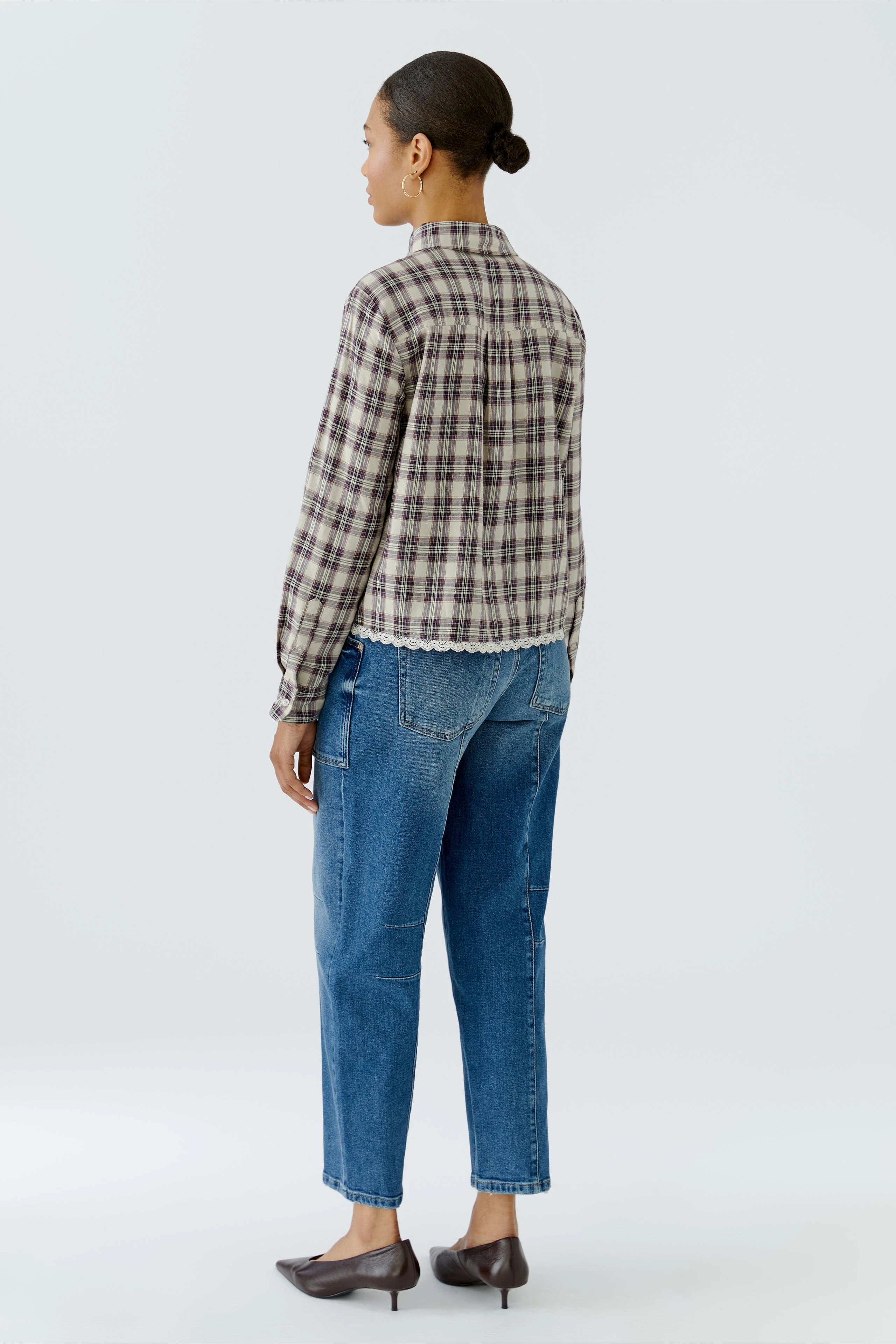 Kariertes Hemdbluse: Frau von hinten in karierter Bluse und blauen Jeans, schlicht und alltagstauglich.