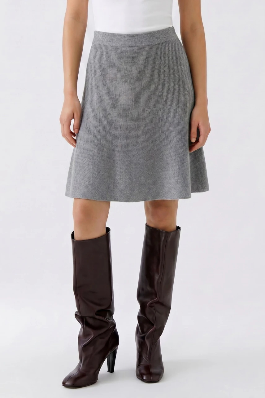Knit skirt: Woman in a gray knit skirt paired with tall brown boots, showcasing a casual style.