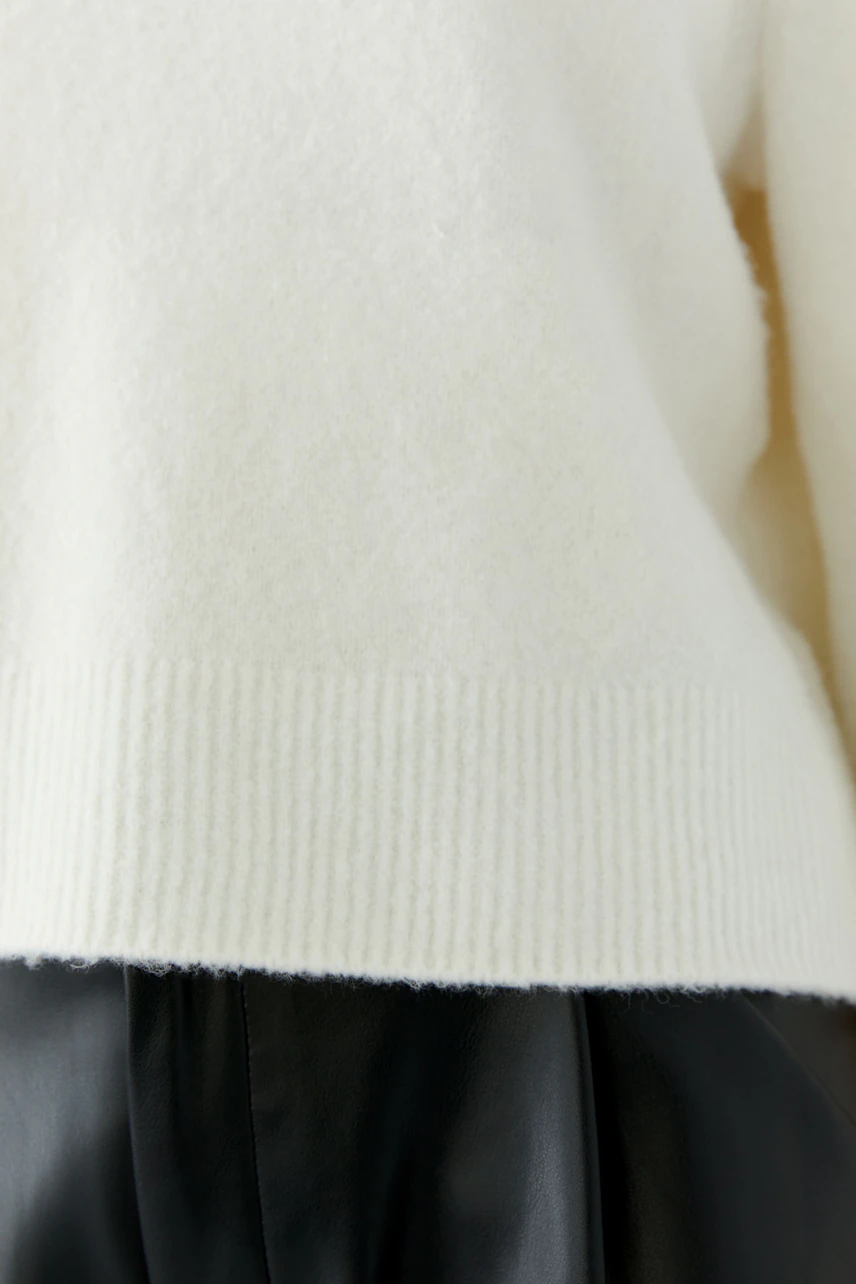 Cozy white pullover with ribbed hem, paired with black leather skirt. No model visible.