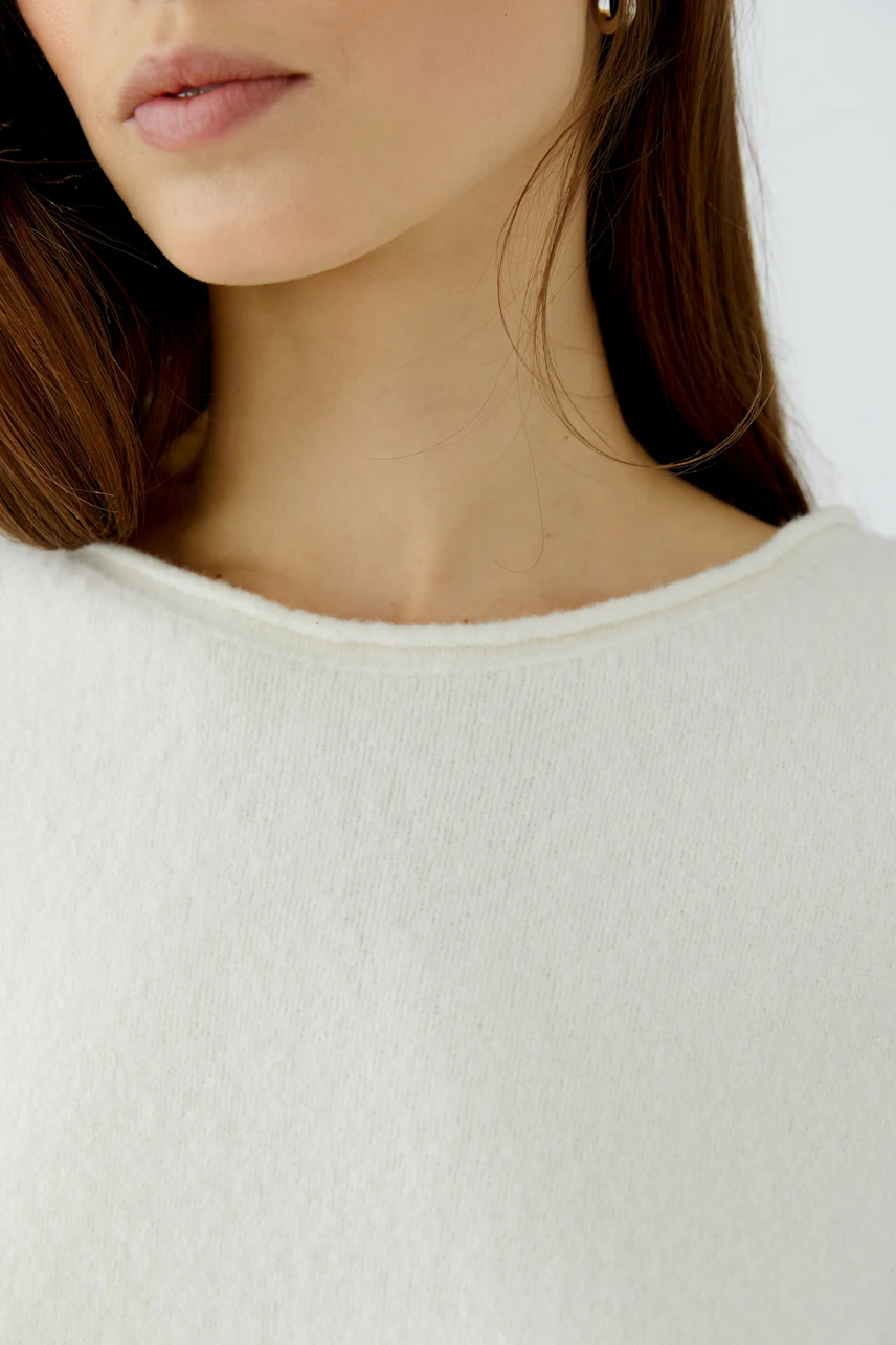 Casual women's pullover: Woman in a soft white pullover with a relaxed fit, showcasing minimalist style.