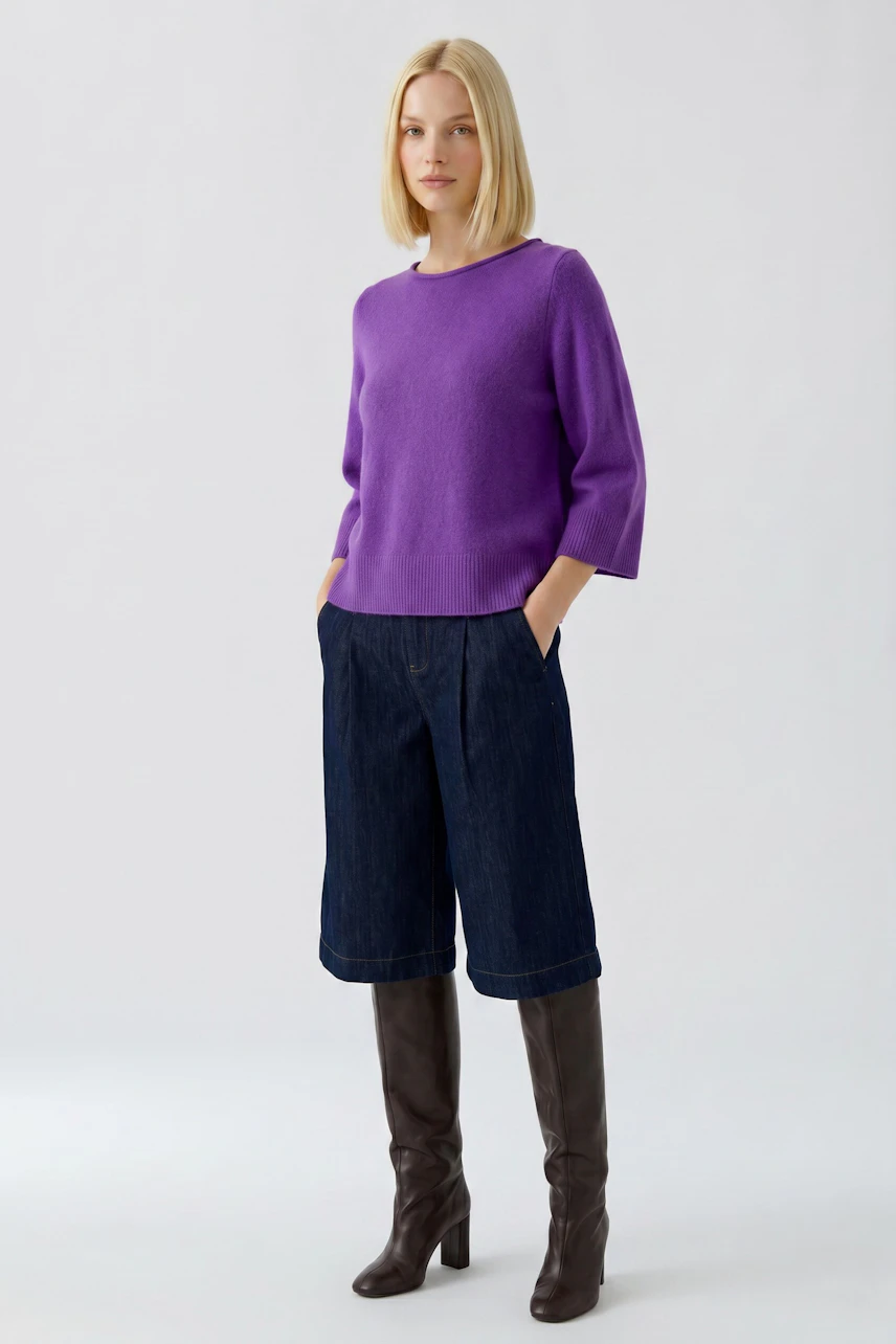 Casual women's pullover: Woman in purple pullover, denim culottes, and knee-high boots stands confidently.
