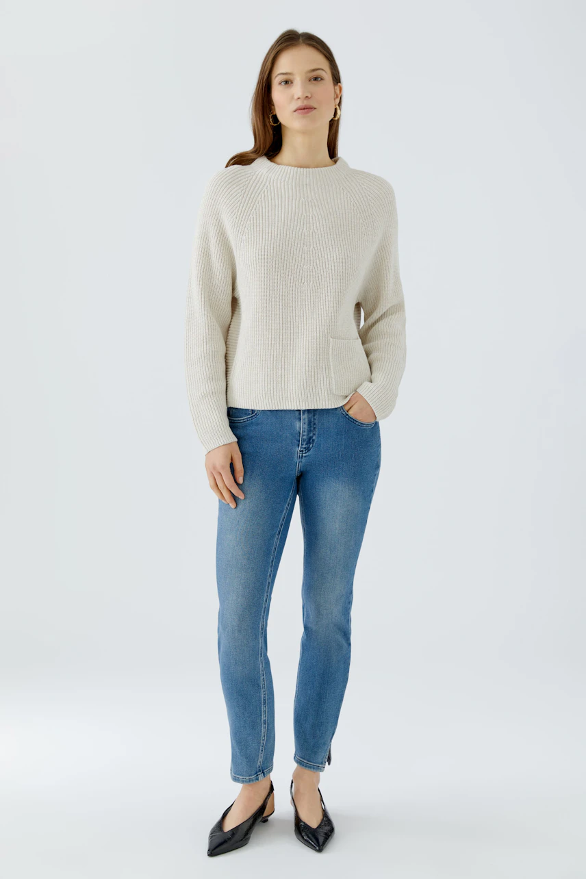 Damen-Pullover: Frau im cremefarbenen Pullover und blauen Jeans, lässig und modern.