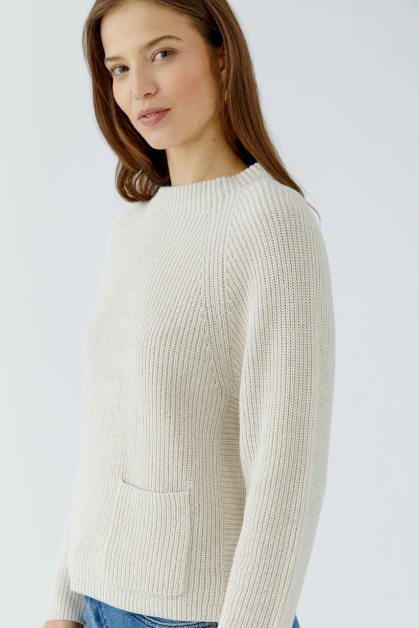Damen-Pullover: Frau im cremefarbenen Strickpullover mit Rundhalsausschnitt und lässigem Look.
