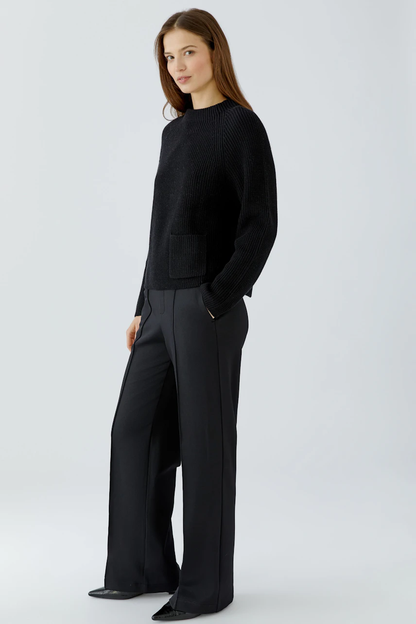 Casual women's pullover: Woman in black pullover with wide-leg pants, exuding a relaxed style.
