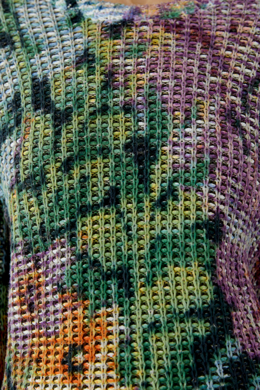 Colorful knit pullover with a vibrant pattern, showcasing a mix of green, purple, and yellow hues.