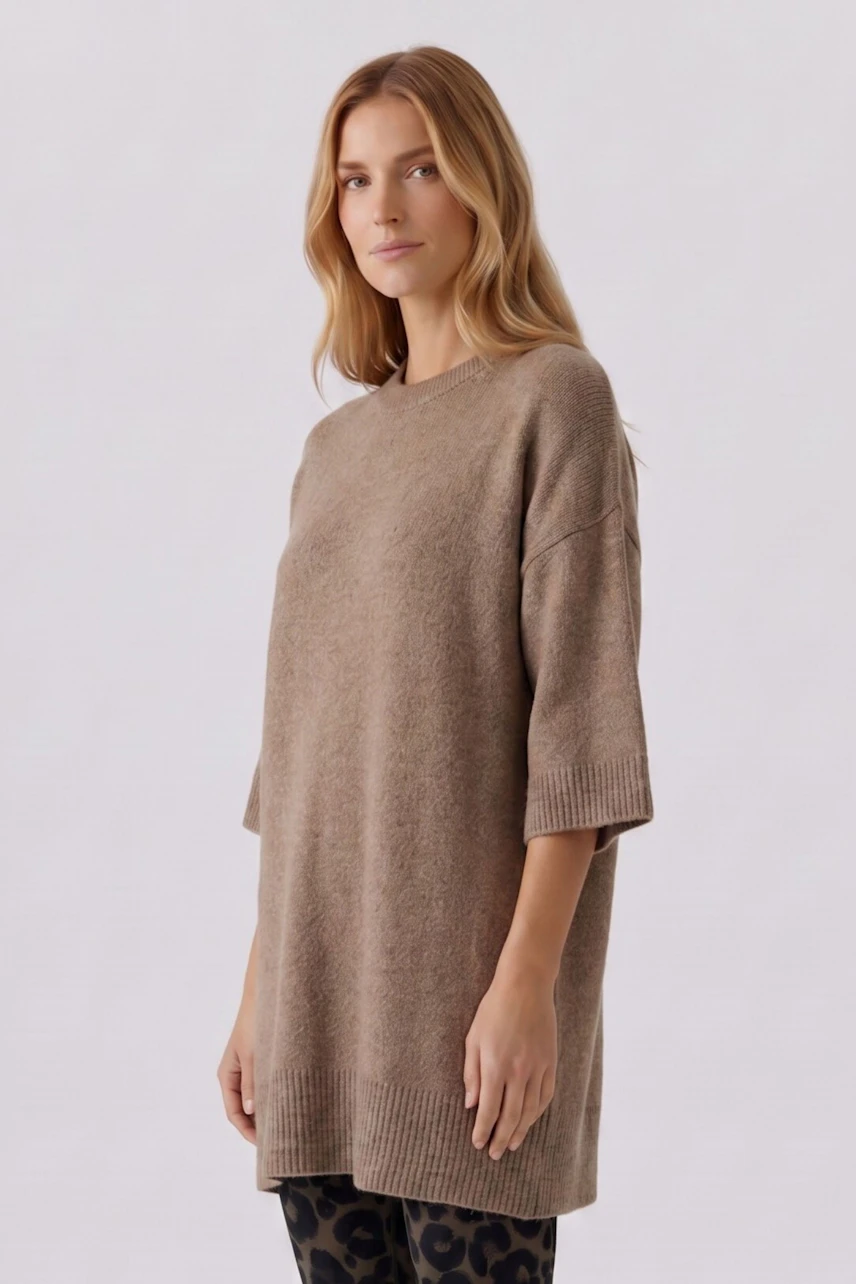 Casual women's pullover: Woman in a loose, beige pullover with half sleeves and patterned leggings.