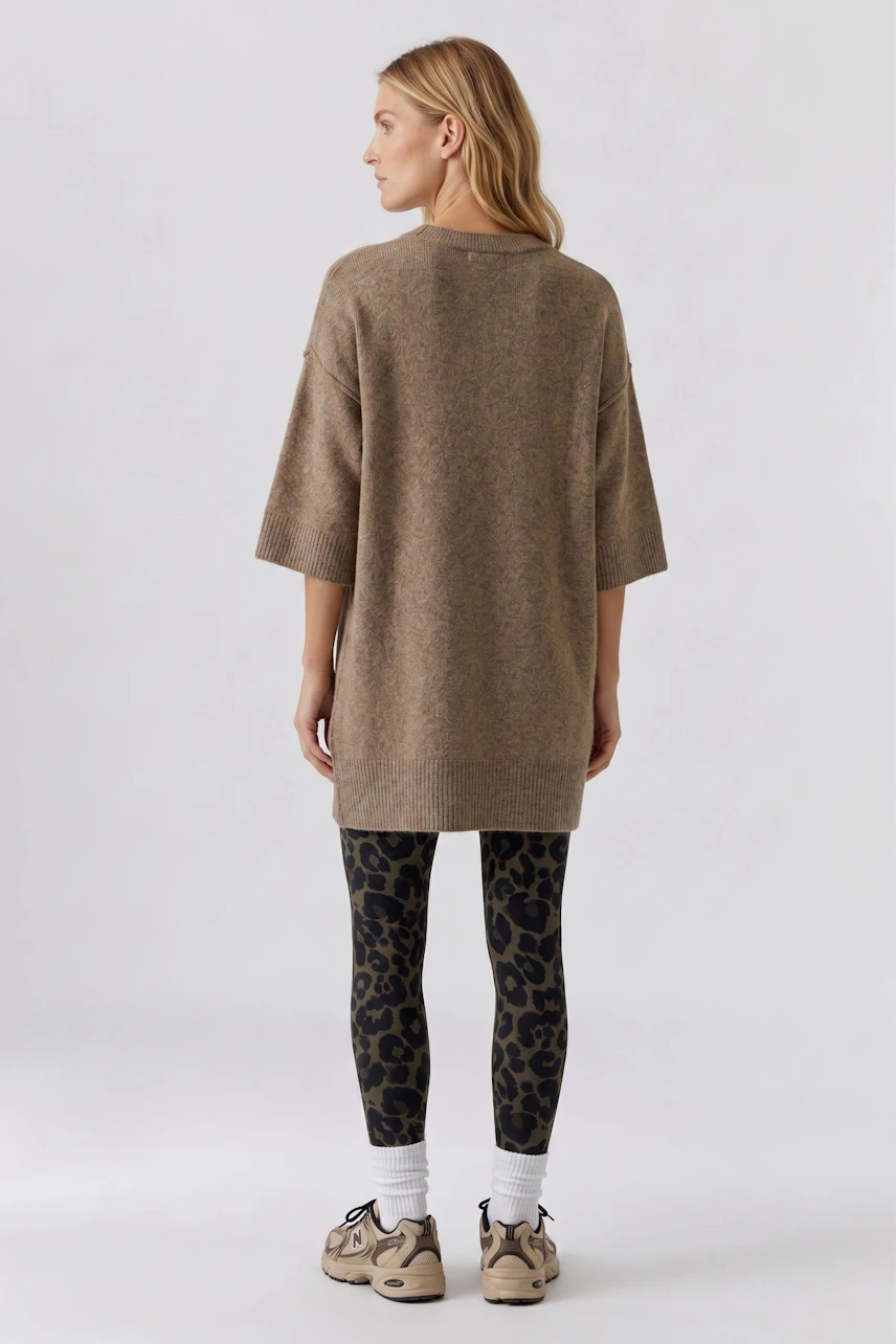 Casual pullover: Woman in a loose brown pullover with leopard print leggings and sneakers, viewed from behind.