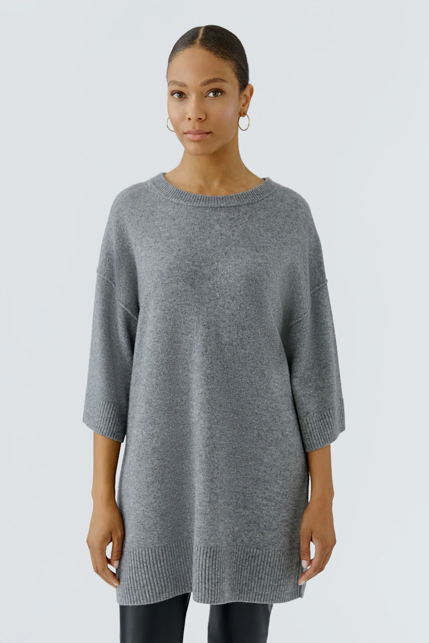 Casual women's pullover: Woman in a relaxed grey pullover with 3/4 sleeves, standing confidently.