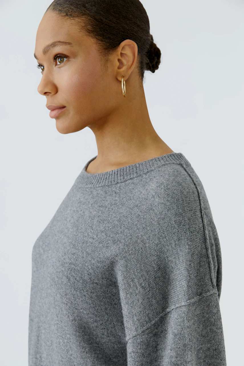 Casual women's pullover: Woman in a grey pullover with a relaxed fit and simple design.