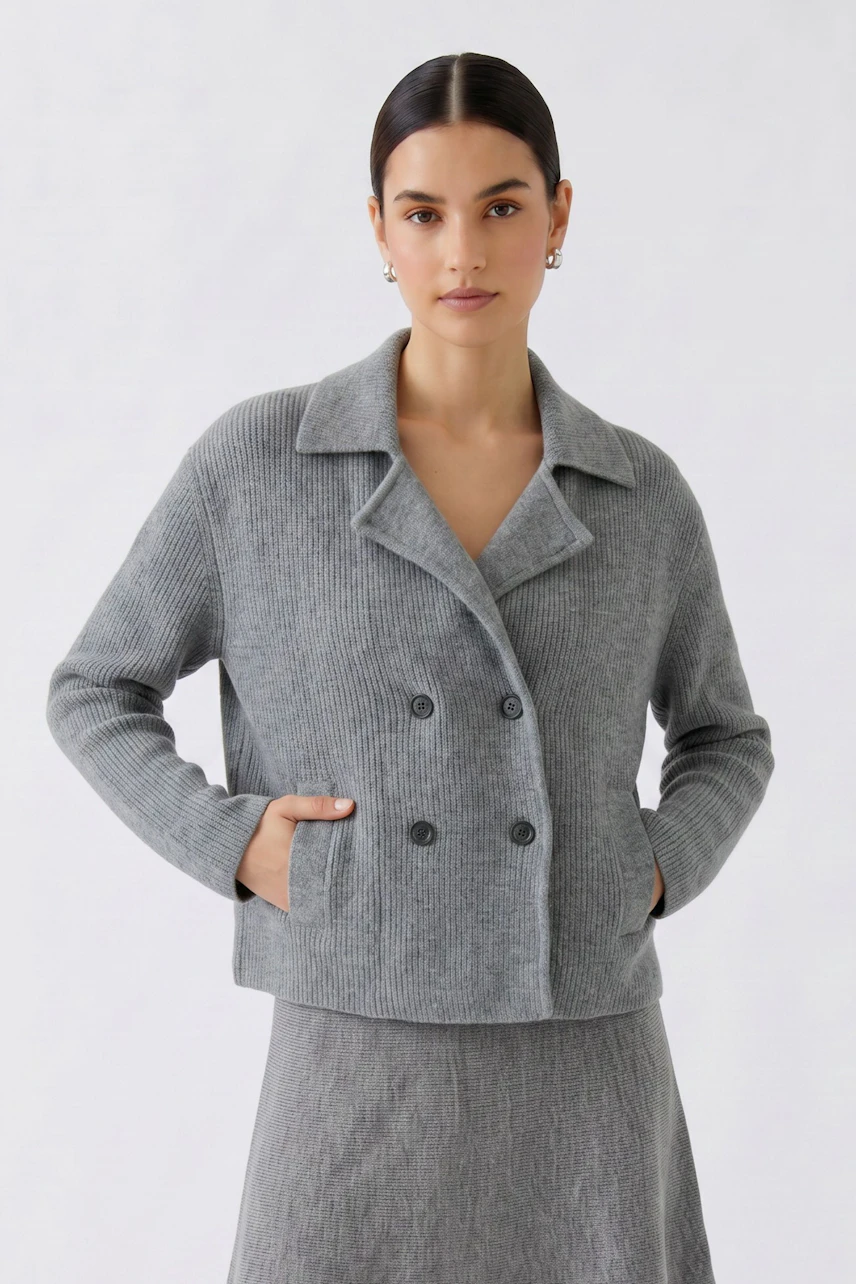 Casual women's cardigan: Woman in a grey double-breasted knit cardigan with matching skirt, hands in pockets.