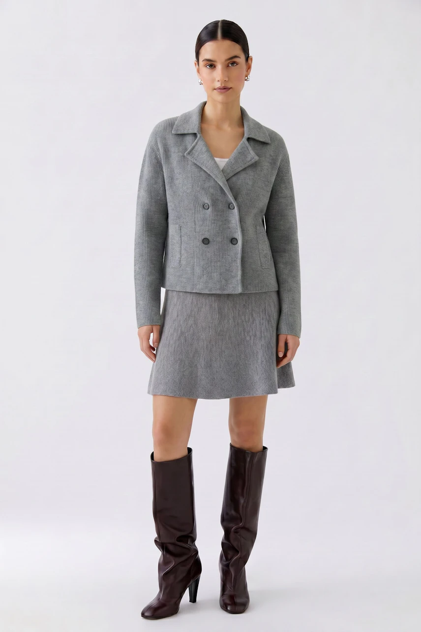 Casual women's cardigan: Woman in a grey knit cardigan with matching skirt and tall brown boots.
