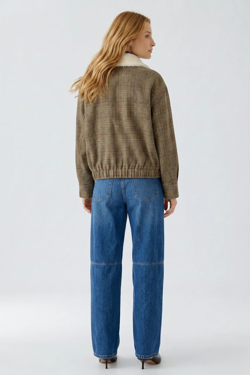 Casual blouson: Woman in a brown checkered blouson with a white collar, paired with blue jeans, facing away.