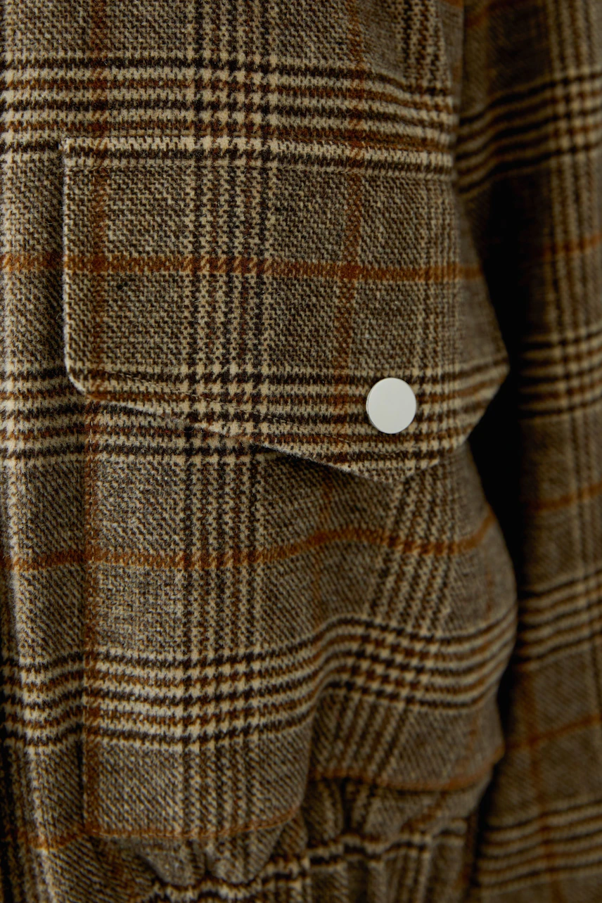 Plaid blouson with buttoned pocket detail, showcasing a casual and stylish design.