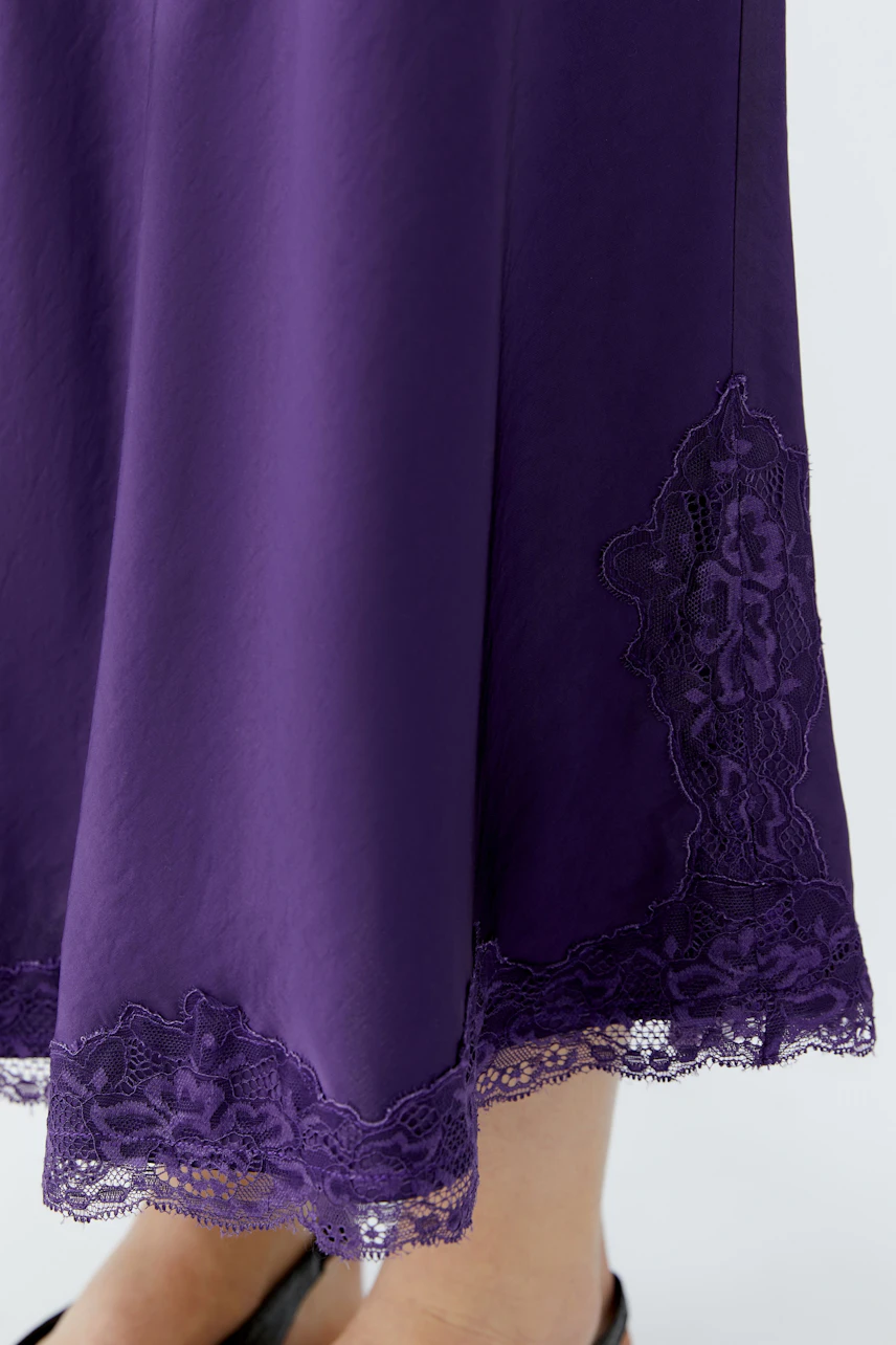 Purple maxi skirt with lace hem detail, worn by a woman. Simple and stylish for any occasion.