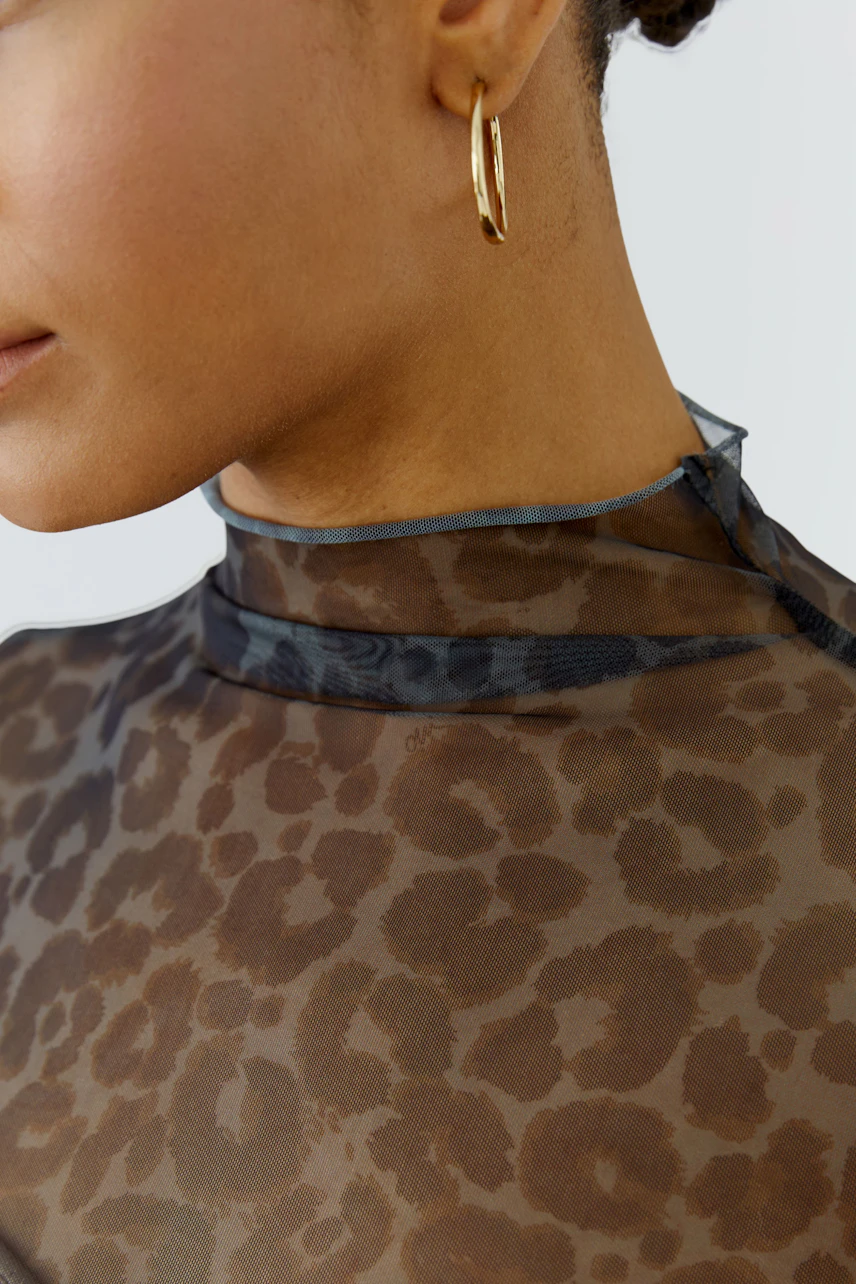 Langarmshirt mit Leopardenmuster: Frau trägt transparentes Shirt mit hohem Kragen und goldenen Ohrringen.