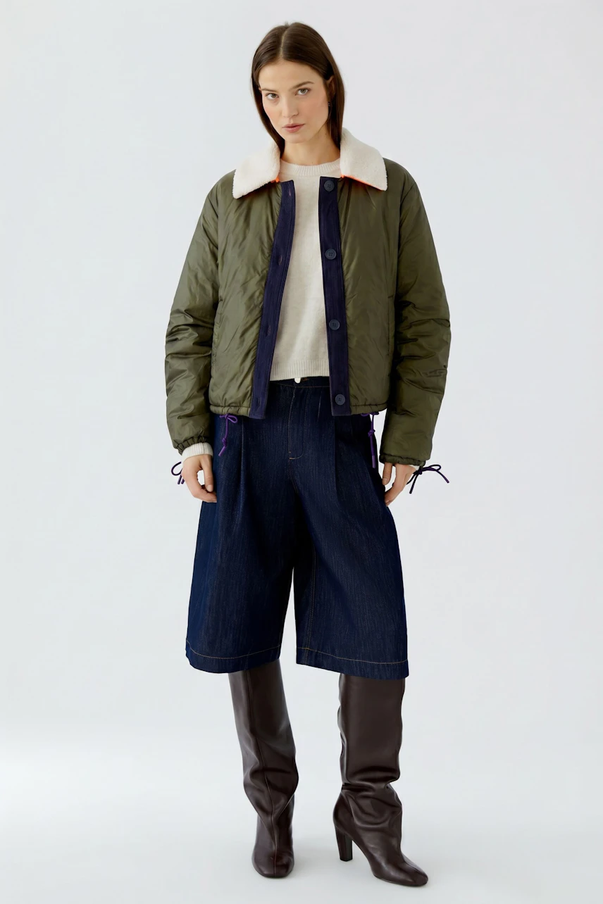 Wendejacke: Frau in olivgrüner Jacke mit hellem Kragen und Jeans. Vielseitig und modern.