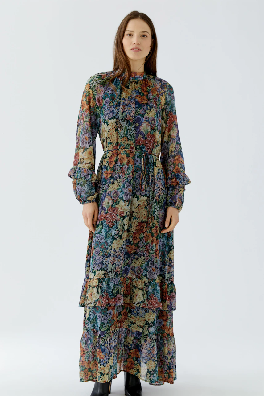 Floral maxi dress: Woman in a colorful, long-sleeved maxi dress with a floral pattern and ruffled details.
