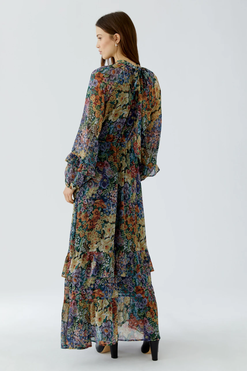 Floral maxi dress: Woman in a colorful, flowing maxi dress with long sleeves and layered skirt.