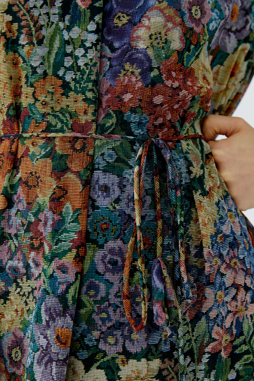 Floral maxi dress: Close-up of colorful floral pattern with a tied waist, showcasing vibrant design.