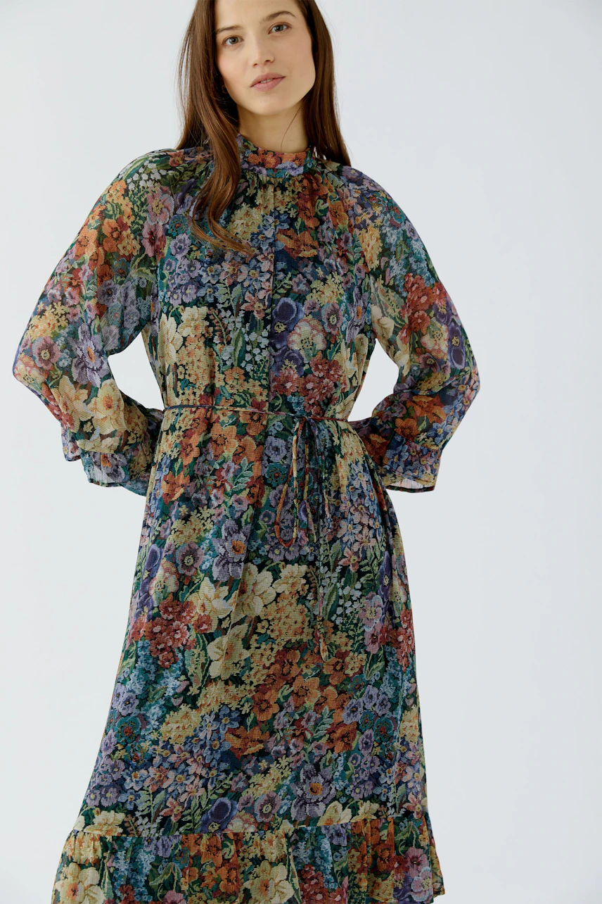 Floral maxi dress: Woman in a colorful floral maxi dress with long sleeves and a relaxed fit.