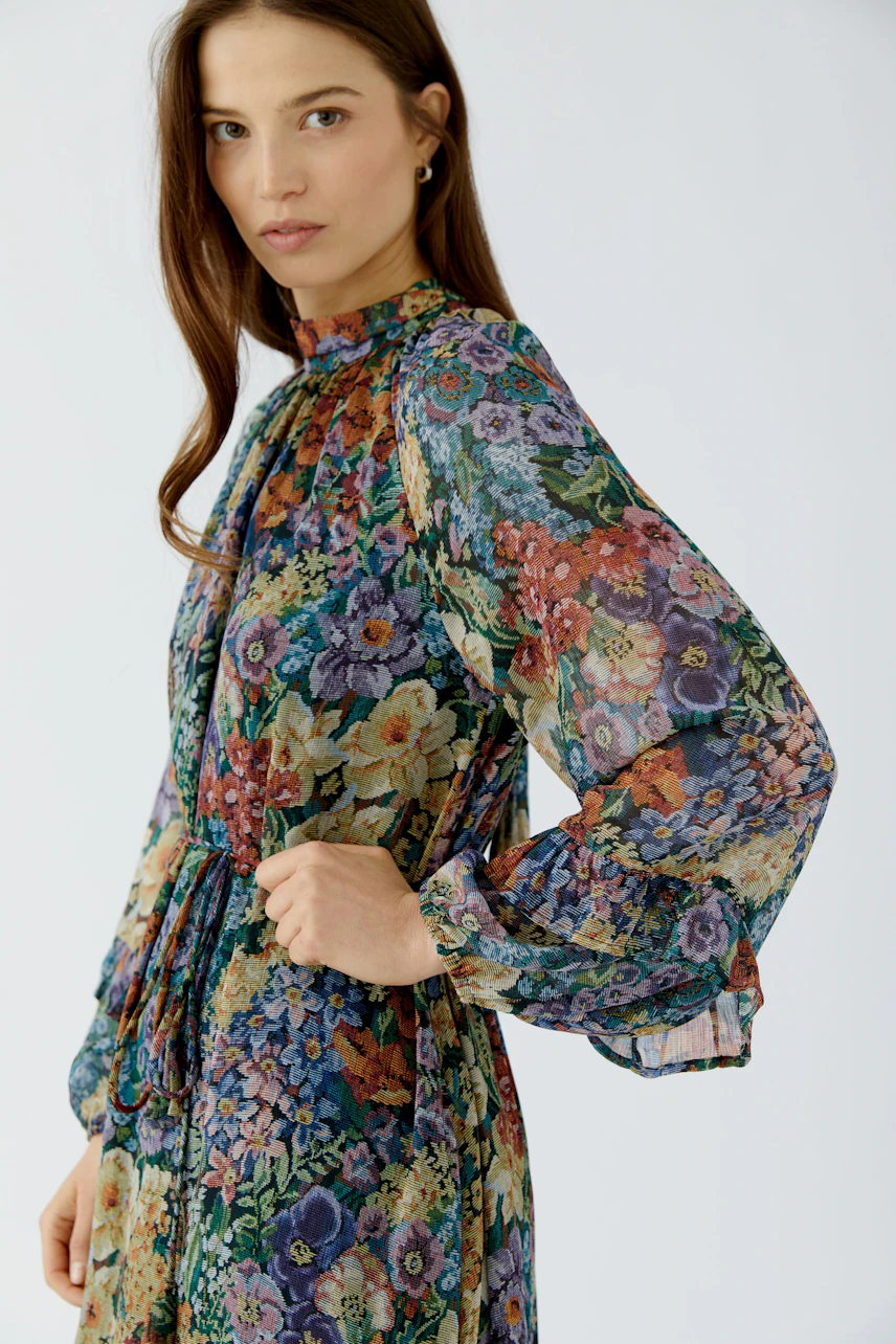 Floral maxi dress: Woman in colorful floral maxi dress with long sleeves, looking confidently.
