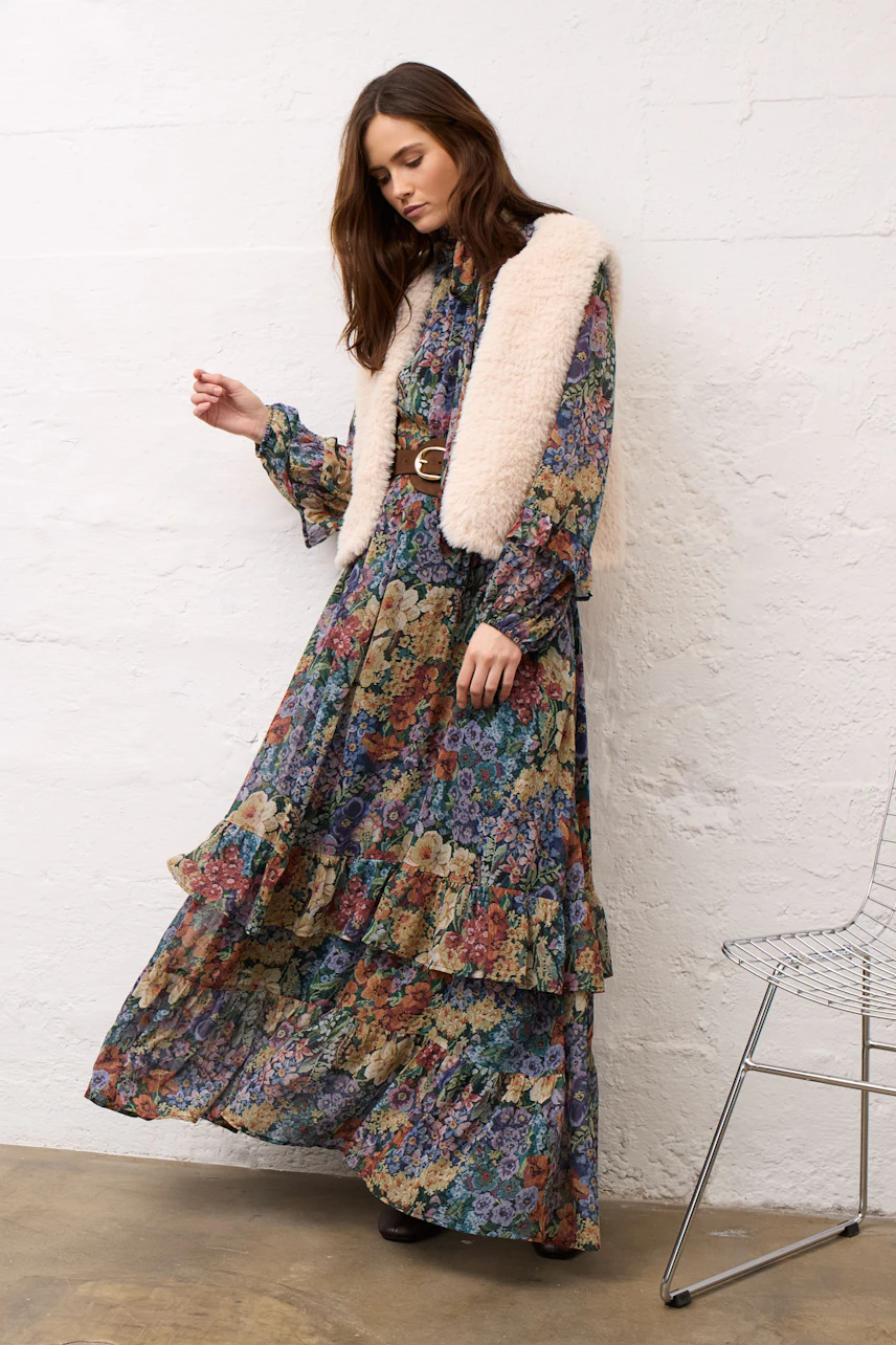 Floral maxi dress: Woman in a colorful floral maxi dress with a fluffy vest, standing gracefully.