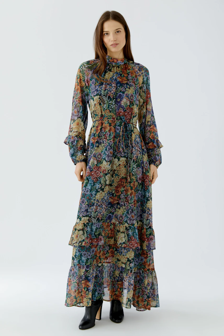 Floral maxi dress: Woman in a colorful, long-sleeved maxi dress with a ruffled hem and floral pattern.