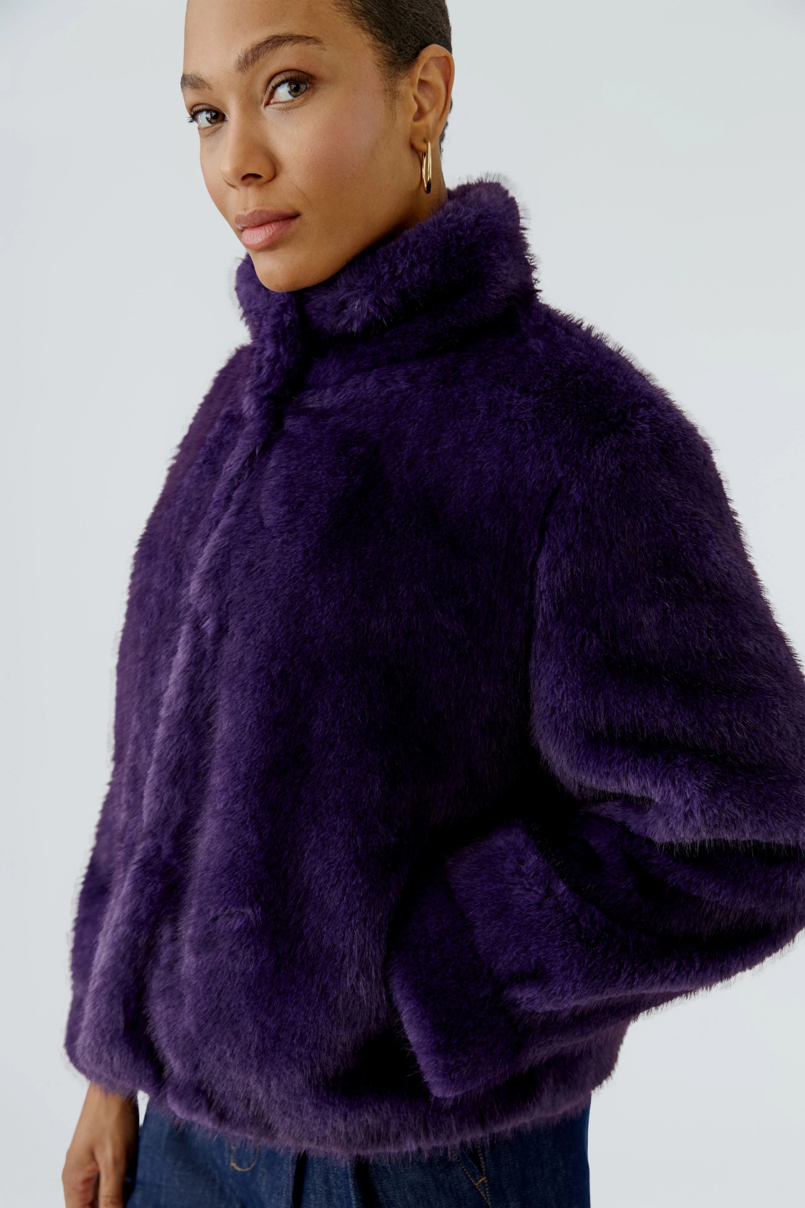 Frau in lila Outdoorjacke: Flauschige Jacke mit hohem Kragen, ideal für kühle Tage.