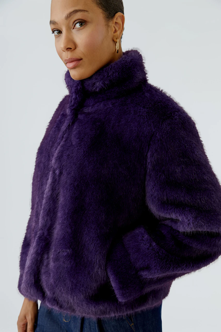 Woman in a purple outdoor jacket, looking confidently. The jacket is fluffy and warm, perfect for cold days.