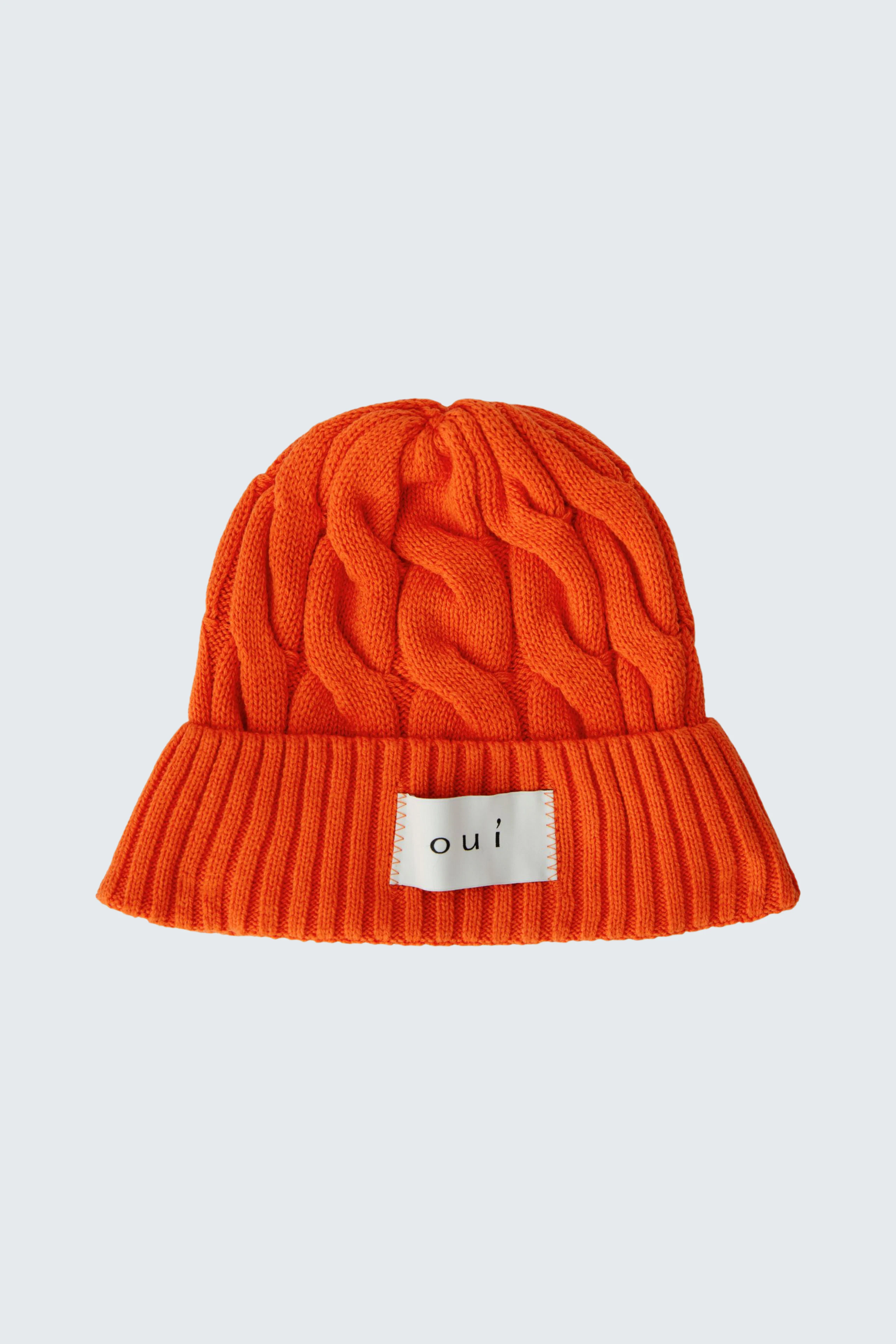 Strickmütze in leuchtendem Orange mit Zopfmuster und Oui-Label, ideal für kalte Tage.