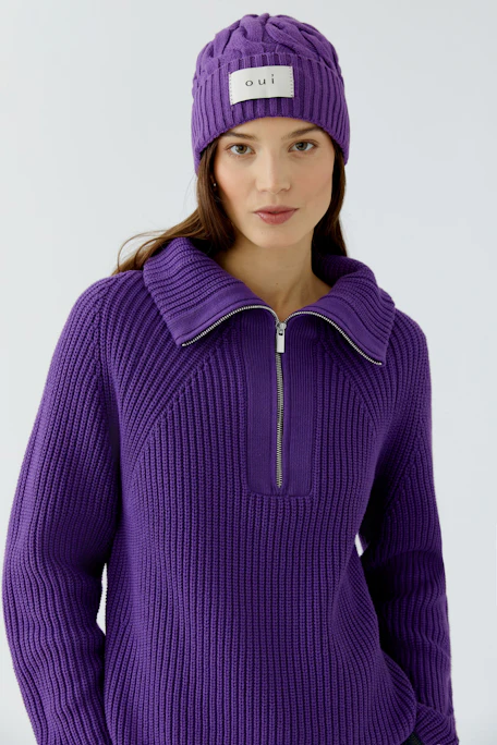 Lila Strickmütze von Oui mit Zopfmuster und Logo-Patch, ideal für kalte Tage.