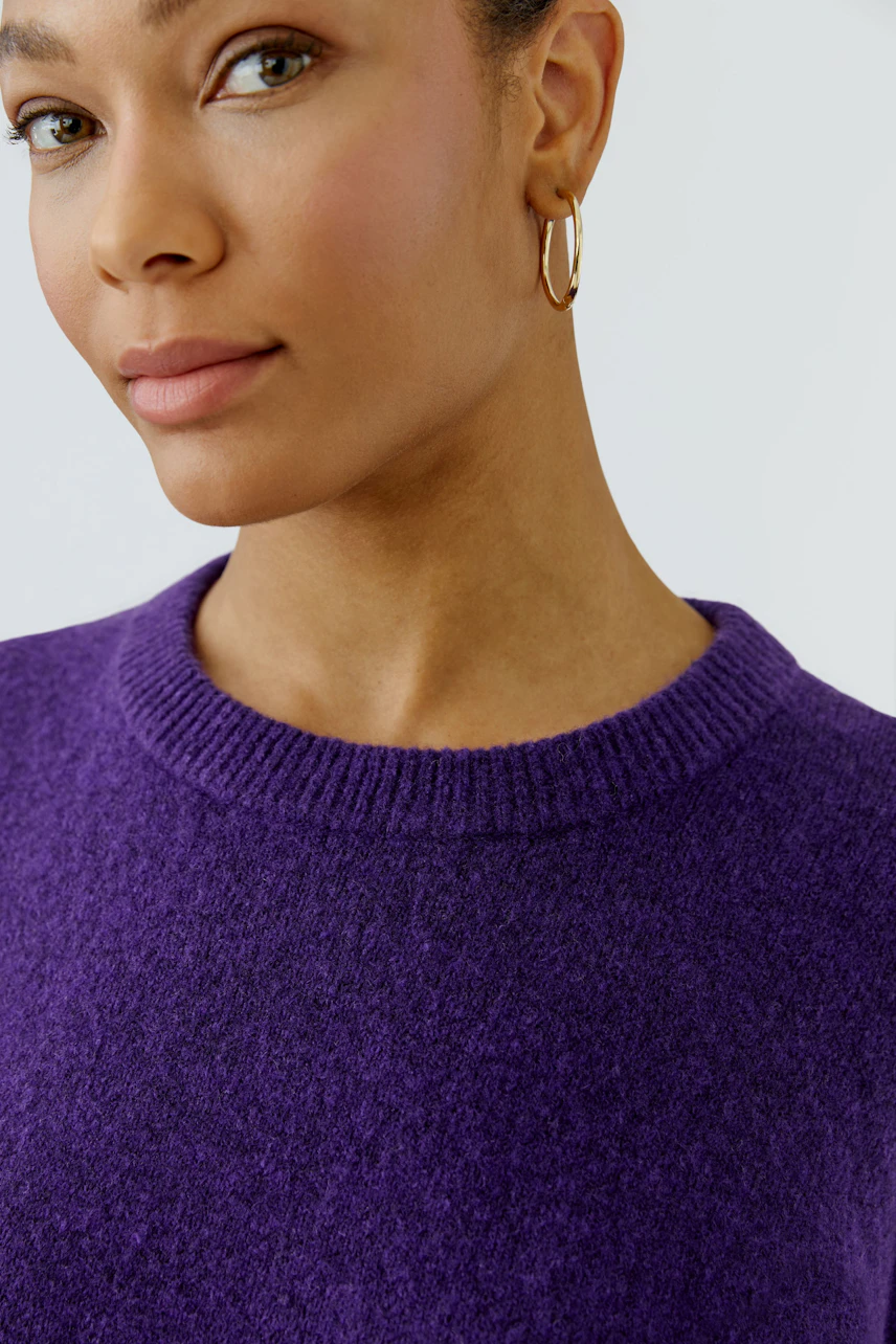 Woman in a vibrant purple pullover, showcasing a casual and confident style.
