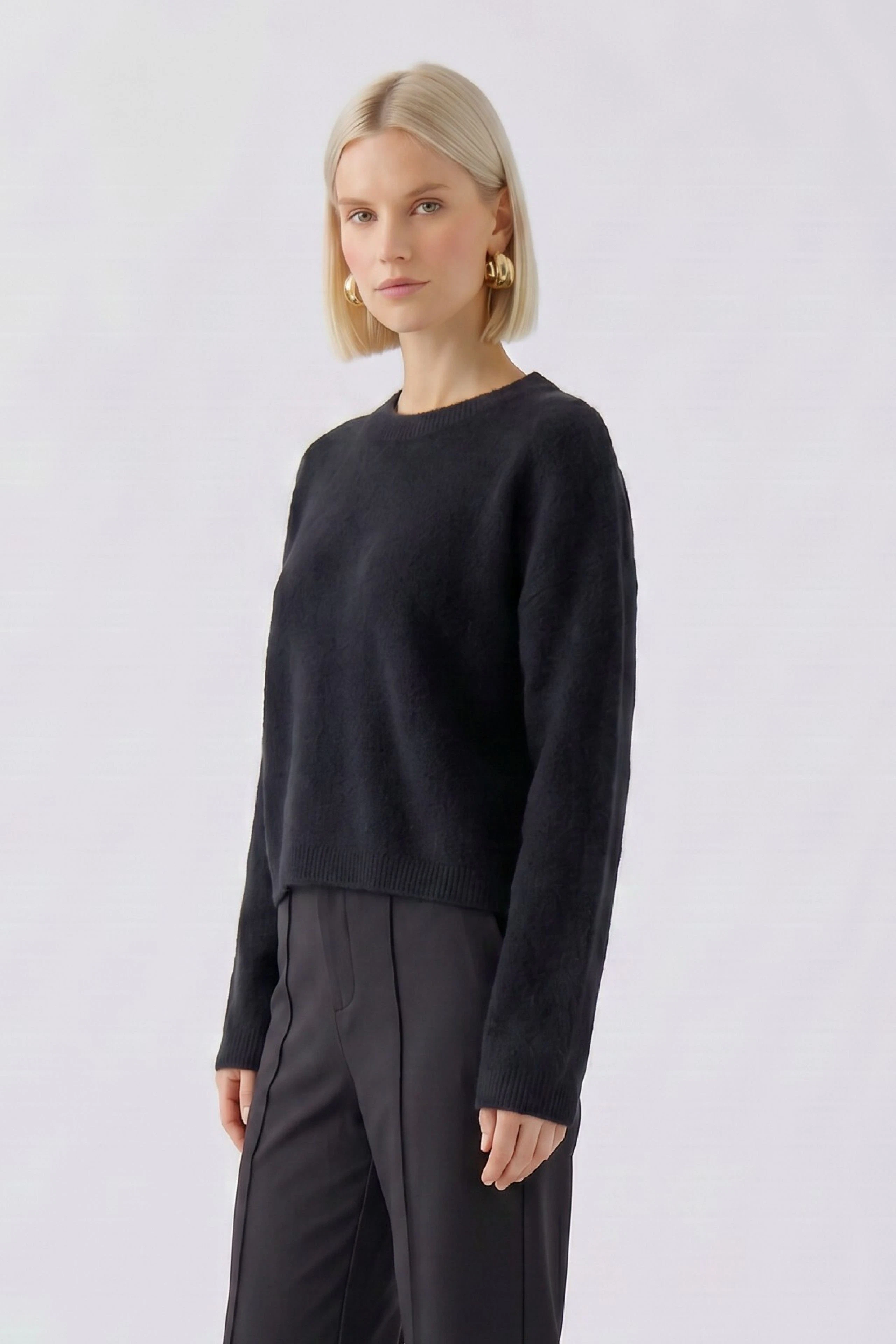 Schlichter Damen-Pullover: Frau im schwarzen Pullover mit langen Ärmeln und geradem Schnitt, dezenter Look.